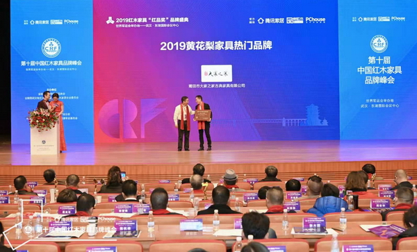 海南花梨文化研究会会长张志扬（左）为“2019黄花梨家具热门品牌”获奖企业——大家之家颁奖
