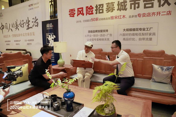 中山雅宋红木总经理窦琦柳(右一)在中国红木三大品类机会优选品牌直播招商会上向观众展示雅宋红木“六面好”家具 中山雅宋红木总经理窦琦柳(右一)在中国红木三大品类机会优选品牌直播招商会上向观众展示雅宋红木“六面好”家具